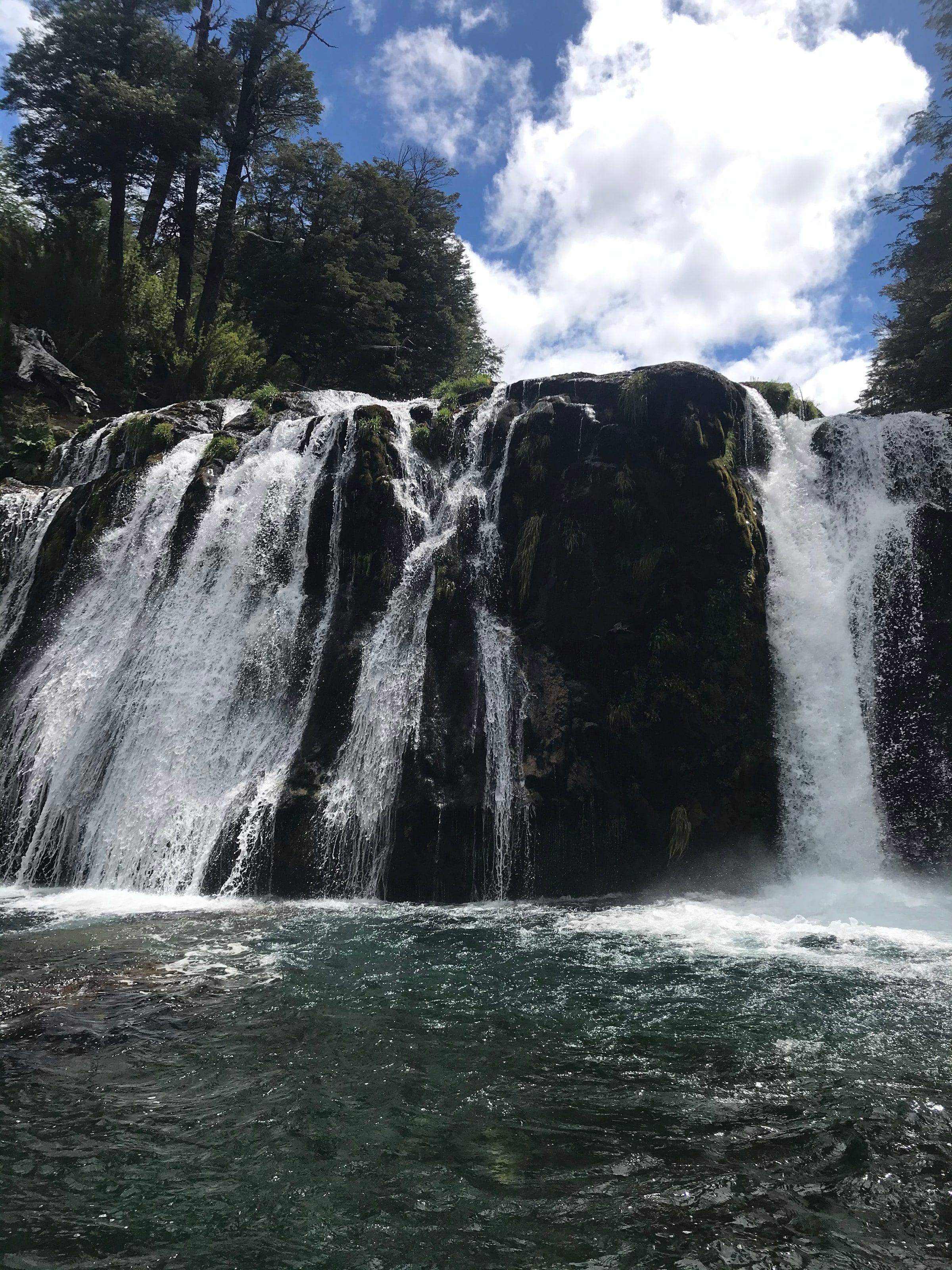 Una cascada ancha cayendo sobre una pileta natural