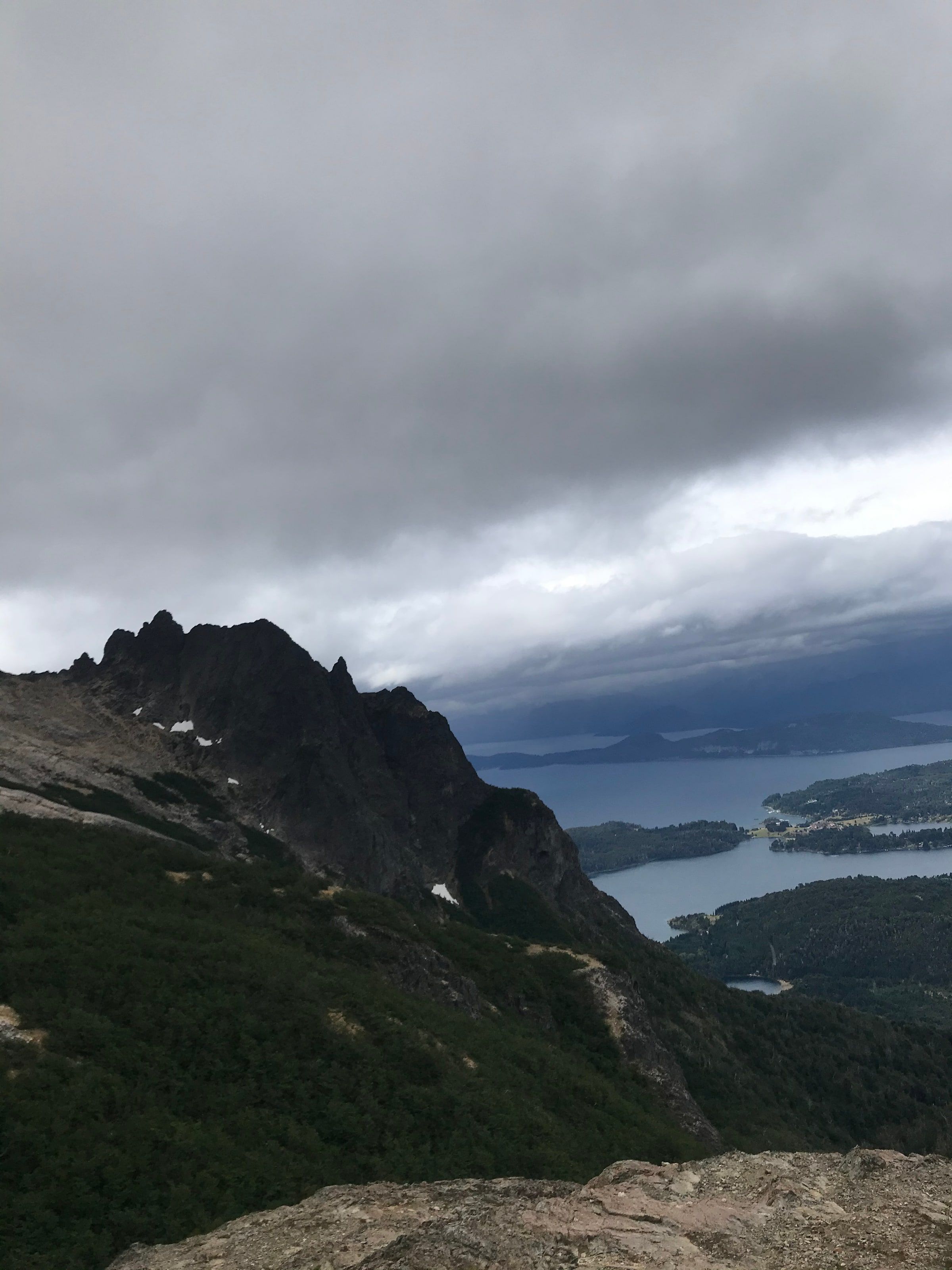 Una montaña de roca con el lago abajo, con nubes