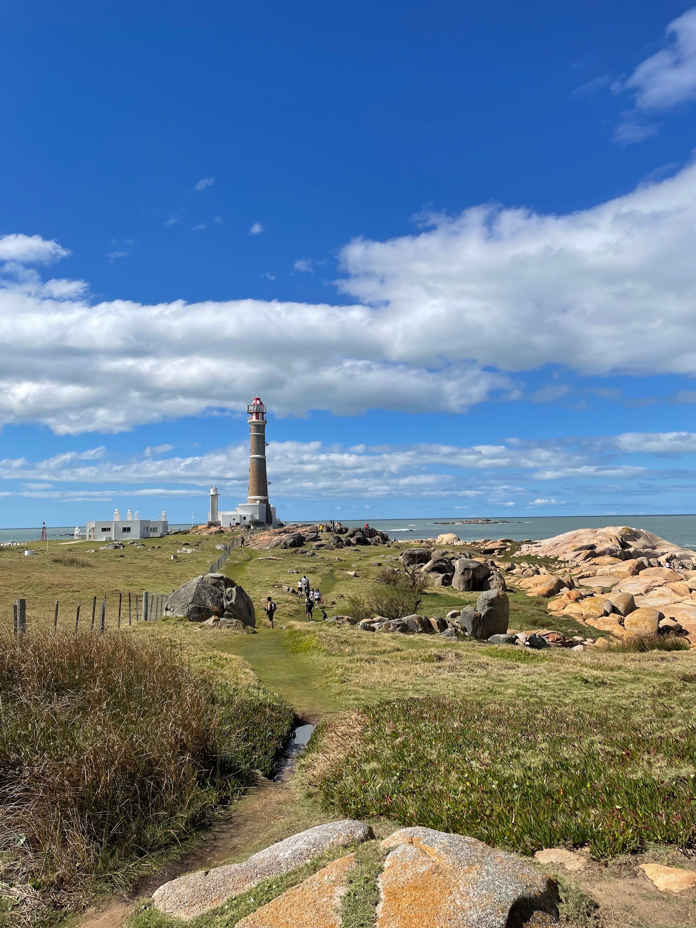 El faro de Cabo Polonio sobre las rocas, con el mar y el cielo con nubes