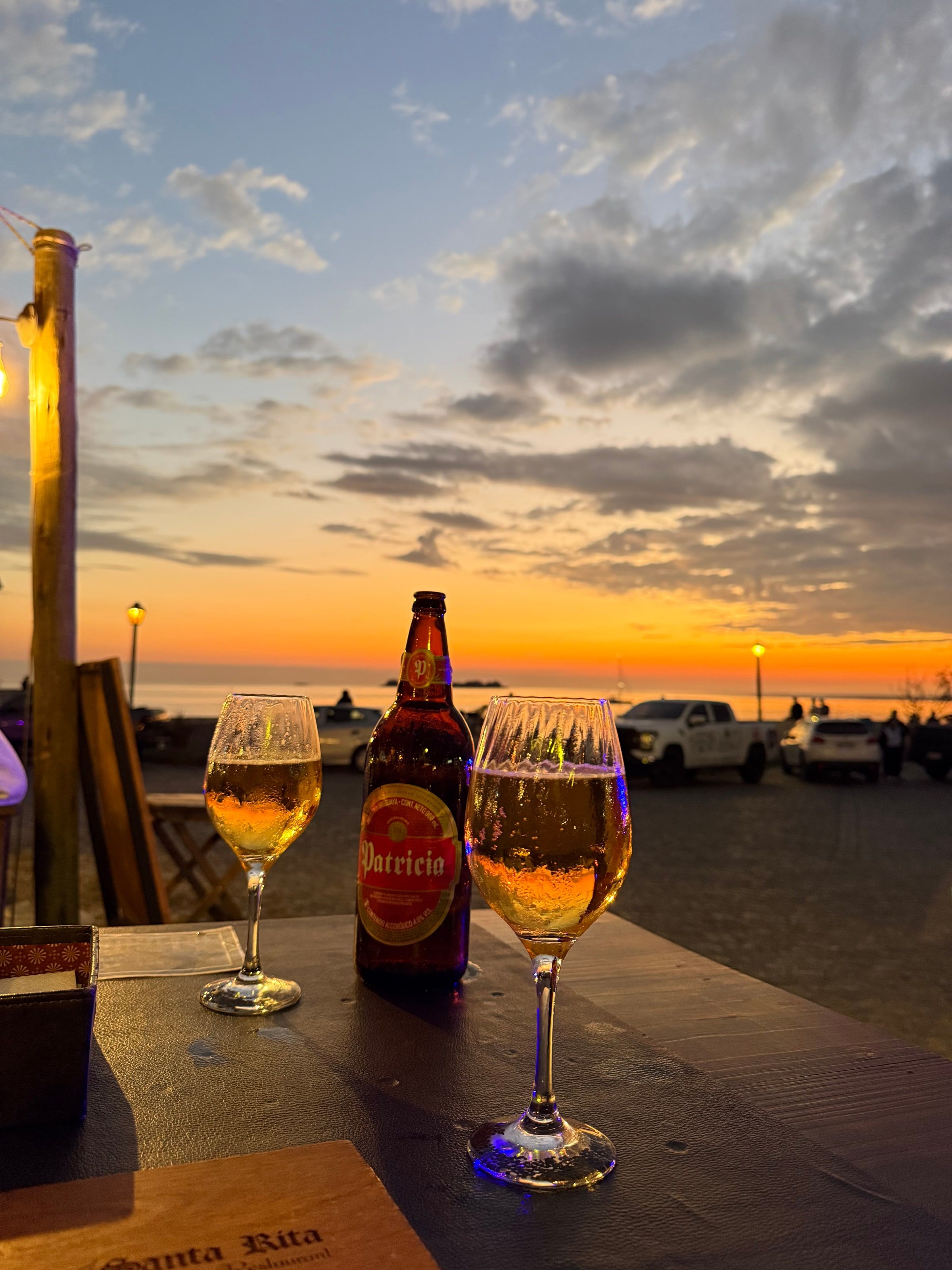 Mesa con copas y una botella frente al atardecer sobre el río