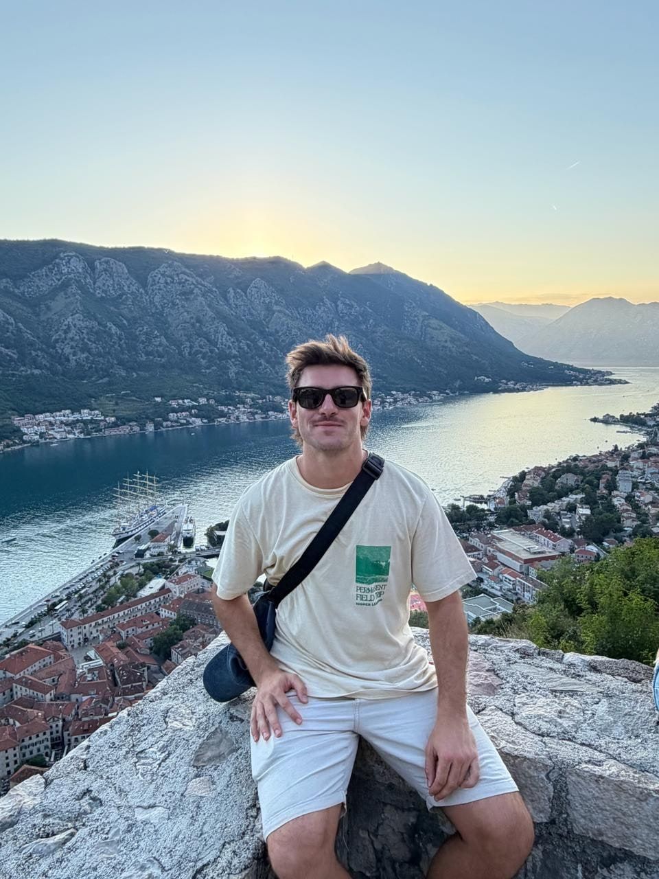 Tomi sentado en una roca con la bahía al atardecer
