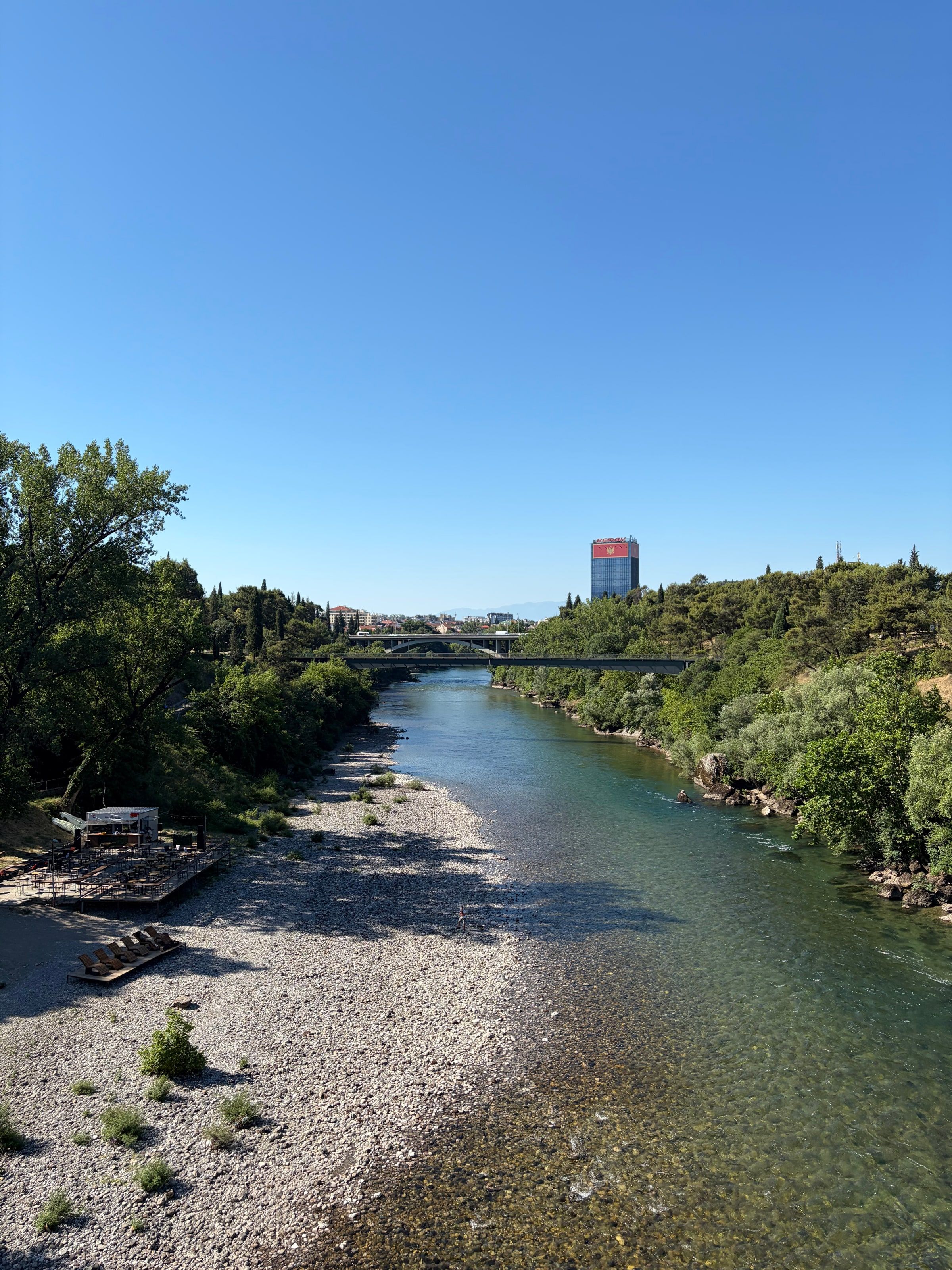 El río Morača entre rocas y árboles, con un puente al fondo
