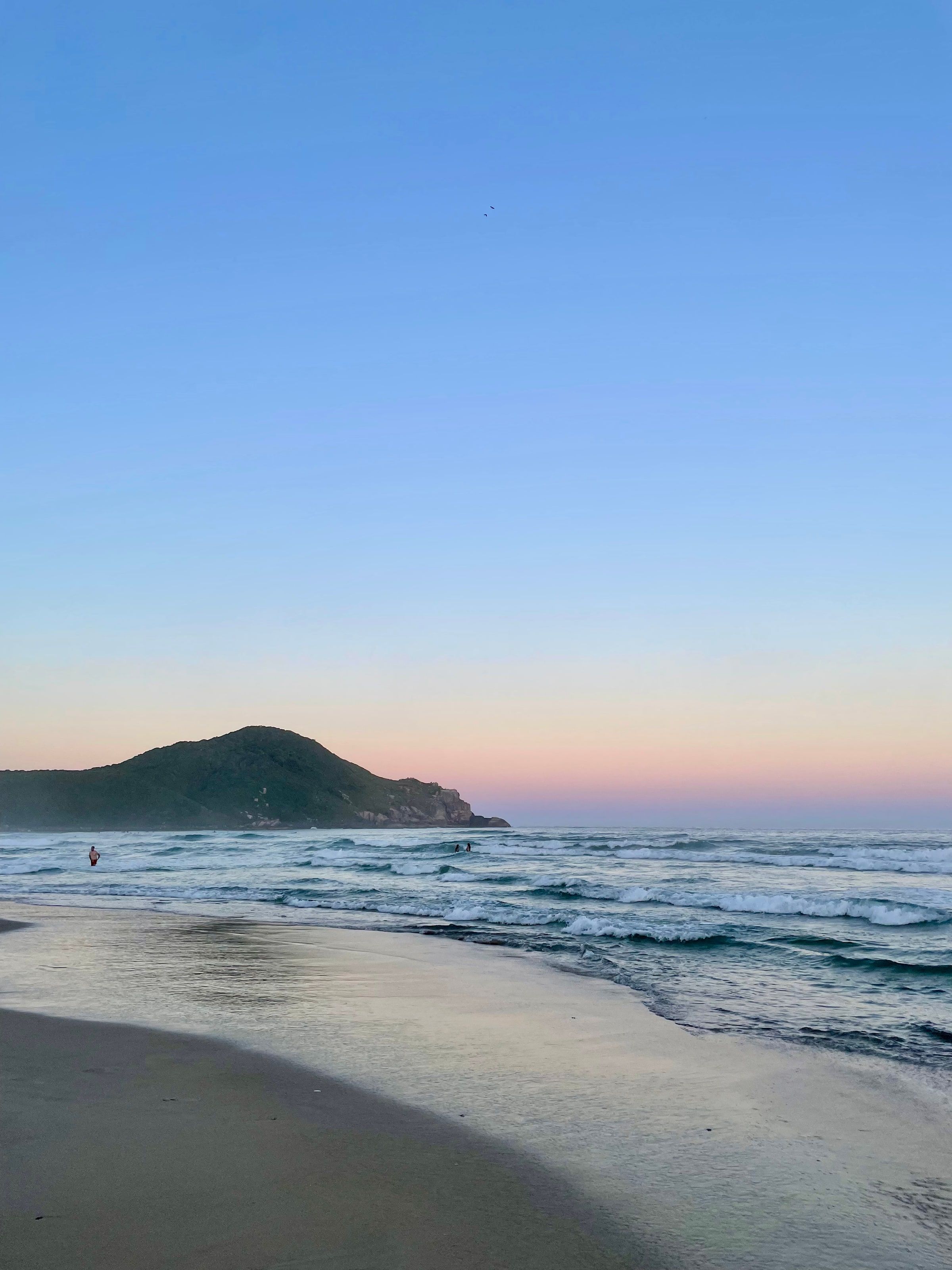 La playa de Praia do Rosa al anochecer, con el cerro al fondo