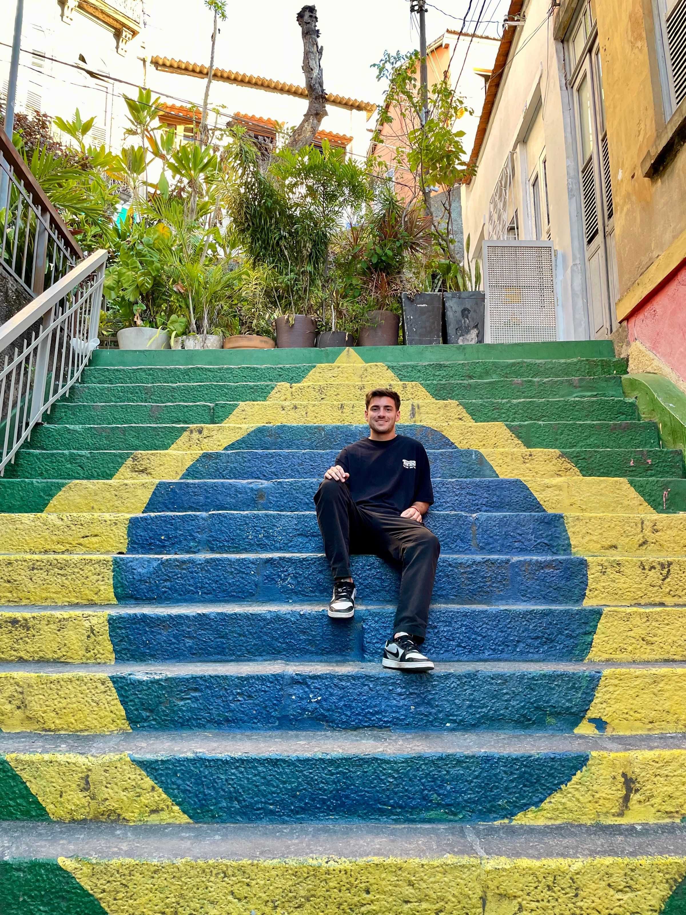 Tomi sentado en una escalera pintada con la bandera de Brasil
