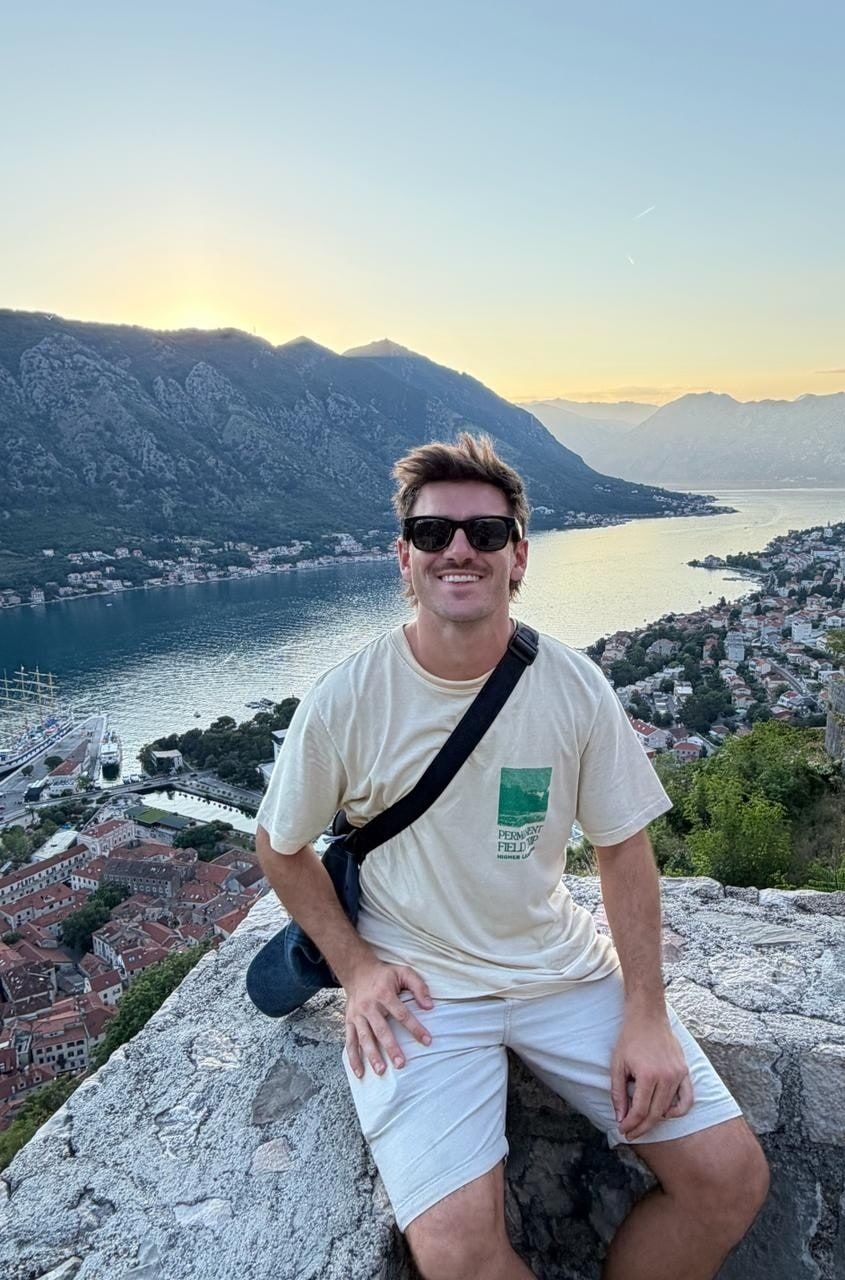 Tomi sentado en la muralla de la fortaleza, con la bahía de Kotor atrás