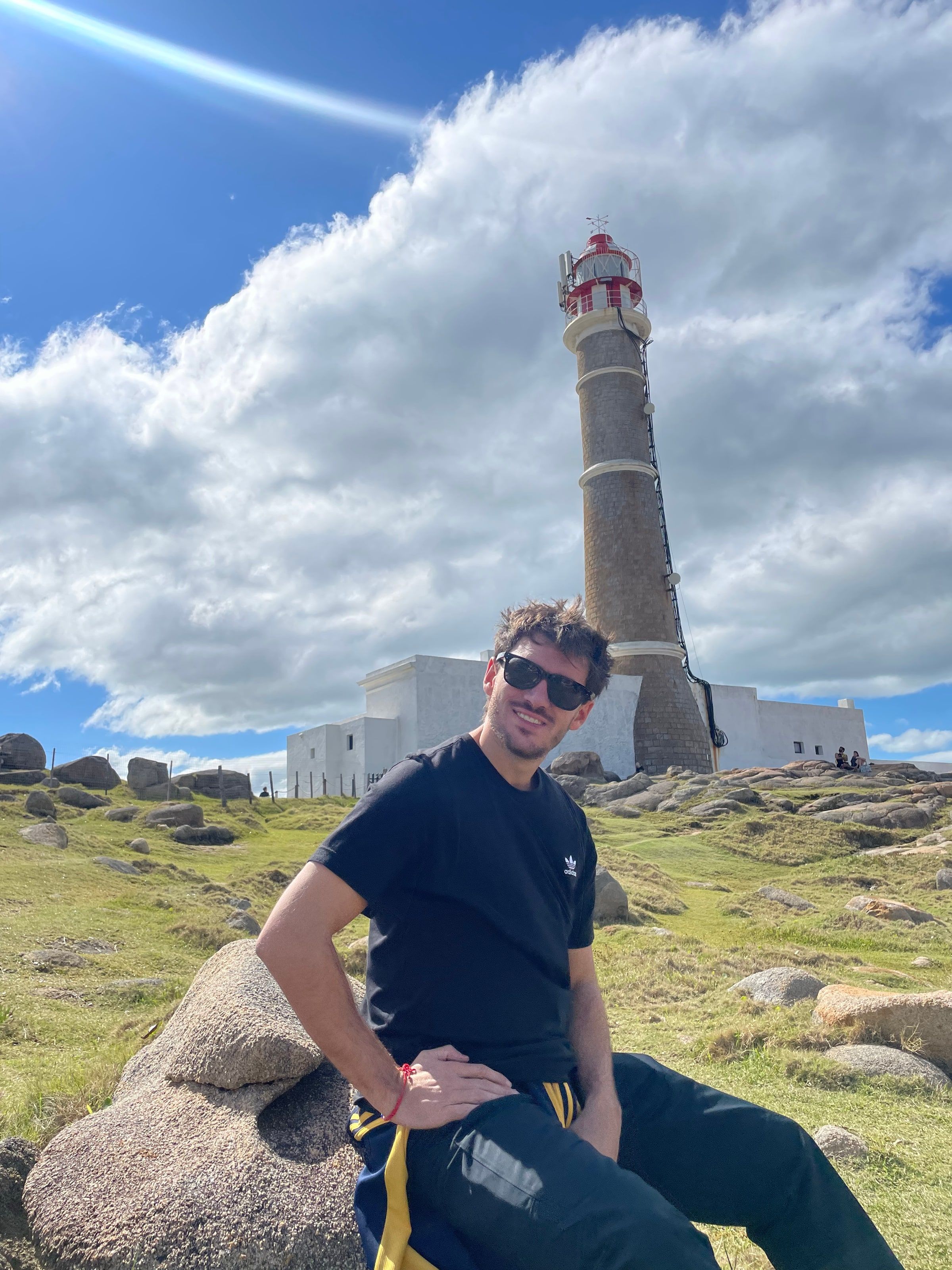Tomi sentado en una roca frente al faro de Cabo Polonio